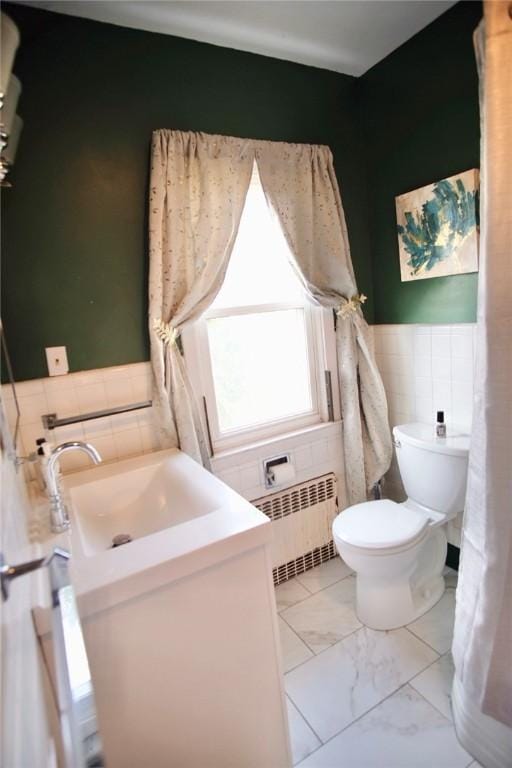 half bathroom featuring vanity, radiator heating unit, tile walls, toilet, and marble finish floor