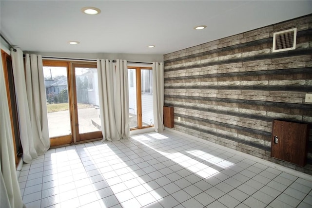 unfurnished room featuring tile patterned flooring, wooden walls, recessed lighting, and visible vents