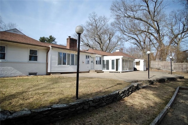 rear view of property featuring brick siding, fence, a chimney, a yard, and a patio