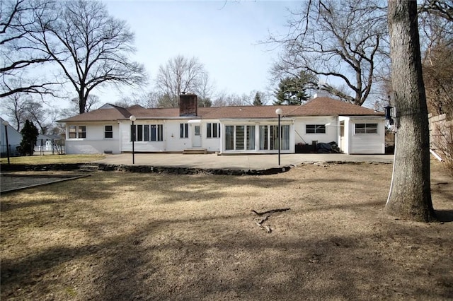 rear view of property featuring a yard, entry steps, a chimney, and a patio area