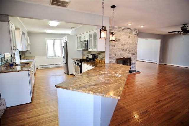 kitchen with a baseboard heating unit, a fireplace, visible vents, and stainless steel appliances