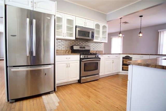 kitchen with stainless steel appliances, white cabinets, glass insert cabinets, light wood-style floors, and backsplash