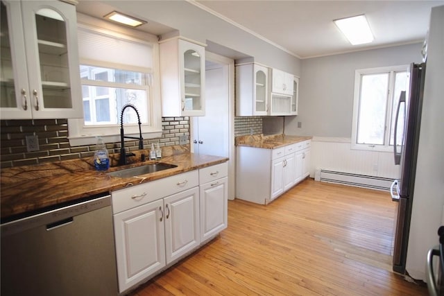 kitchen featuring a wainscoted wall, light wood-style flooring, a sink, appliances with stainless steel finishes, and a baseboard heating unit