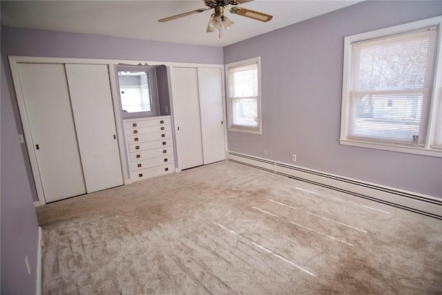 unfurnished bedroom featuring a baseboard radiator, multiple closets, a ceiling fan, and carpet flooring