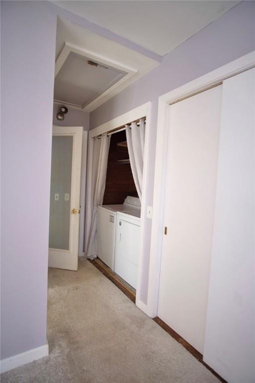 corridor with light colored carpet and washer and clothes dryer