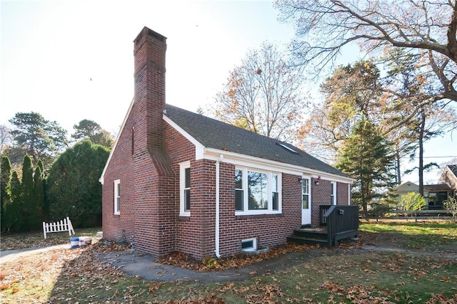 view of property exterior with brick siding, a chimney, and a yard