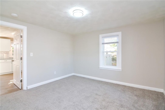 unfurnished room featuring light carpet and baseboards