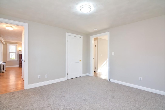 unfurnished bedroom with radiator heating unit, carpet, and baseboards