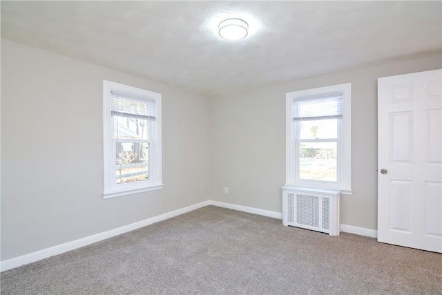 carpeted spare room featuring radiator heating unit, baseboards, and plenty of natural light