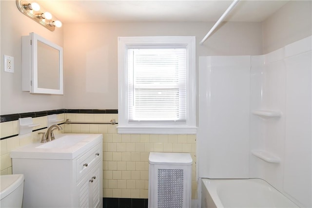 bathroom featuring a wainscoted wall, vanity, toilet, and tile walls