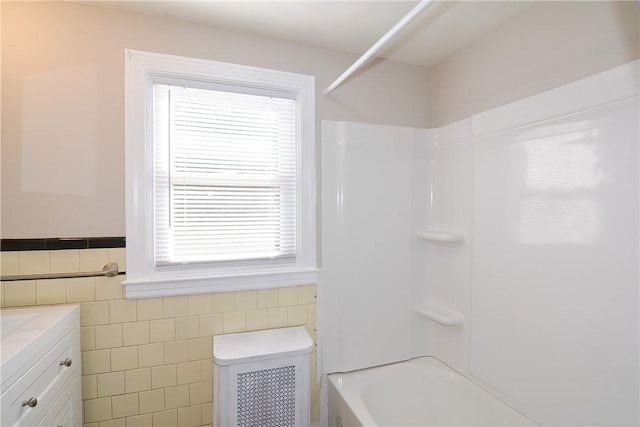 bathroom with a wainscoted wall, toilet, tile walls, tub / shower combination, and vanity