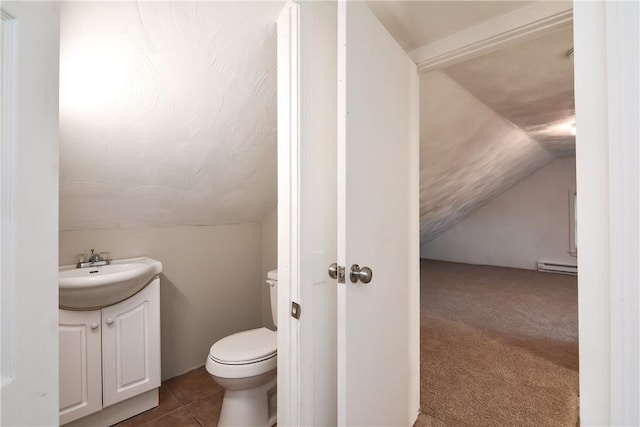 half bathroom featuring tile patterned floors, toilet, baseboard heating, vanity, and vaulted ceiling