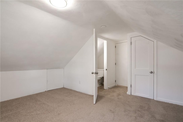 additional living space featuring light colored carpet and vaulted ceiling