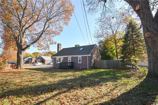 rear view of property with a yard, brick siding, a chimney, and fence