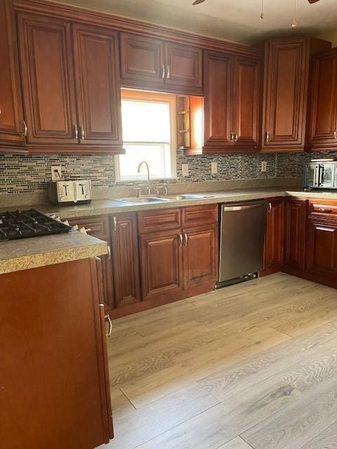 kitchen featuring light wood finished floors, dishwasher, ceiling fan, and a sink