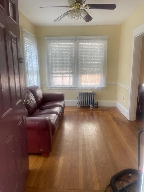 sitting room with ceiling fan, radiator heating unit, baseboards, and wood finished floors