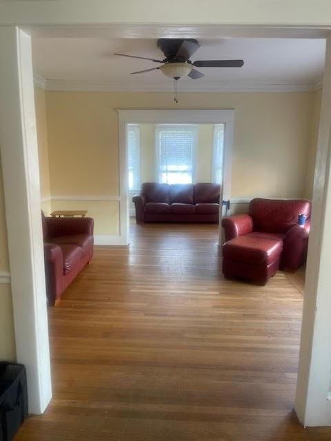 unfurnished living room with ceiling fan, wood finished floors, and ornamental molding