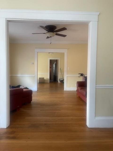 hallway with wood finished floors and ornamental molding