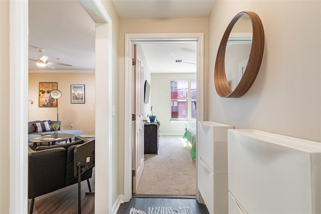 hallway with baseboards, carpet floors, wood finished floors, and ornamental molding