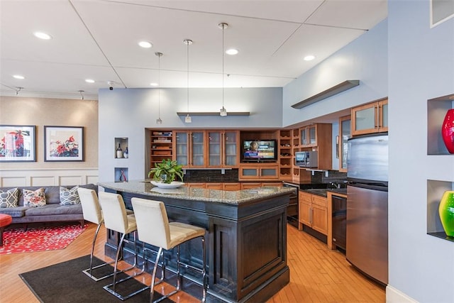 kitchen with light wood-style flooring, a breakfast bar area, stainless steel appliances, and glass insert cabinets