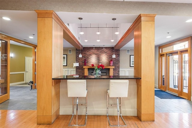 kitchen with dark countertops, a breakfast bar area, wood-type flooring, and pendant lighting