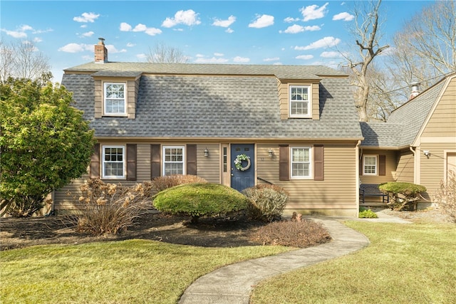 colonial inspired home with a chimney, a shingled roof, and a front lawn