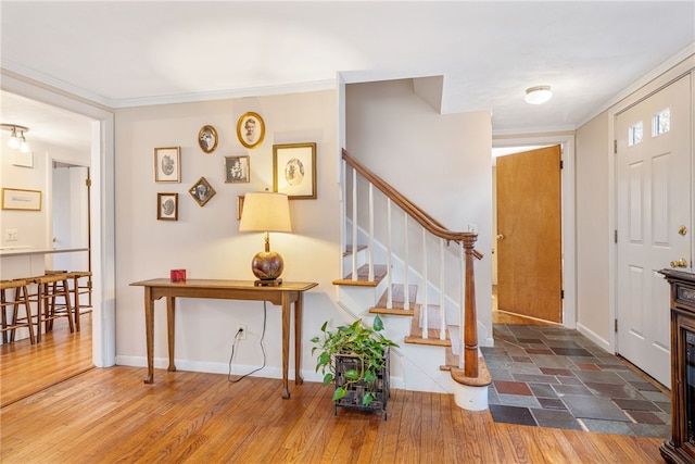 foyer entrance featuring crown molding, stairway, wood finished floors, and baseboards