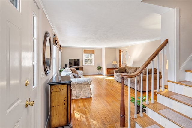 living area featuring stairway, light wood-style flooring, and ornamental molding