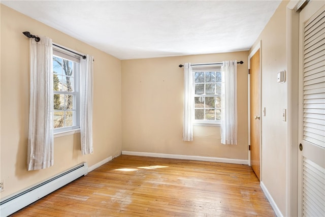 spare room with baseboards, light wood-style floors, and a baseboard radiator