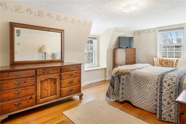 bedroom featuring light wood finished floors, multiple windows, and baseboards