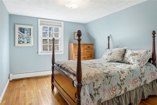 bedroom with baseboard heating, baseboards, and hardwood / wood-style floors