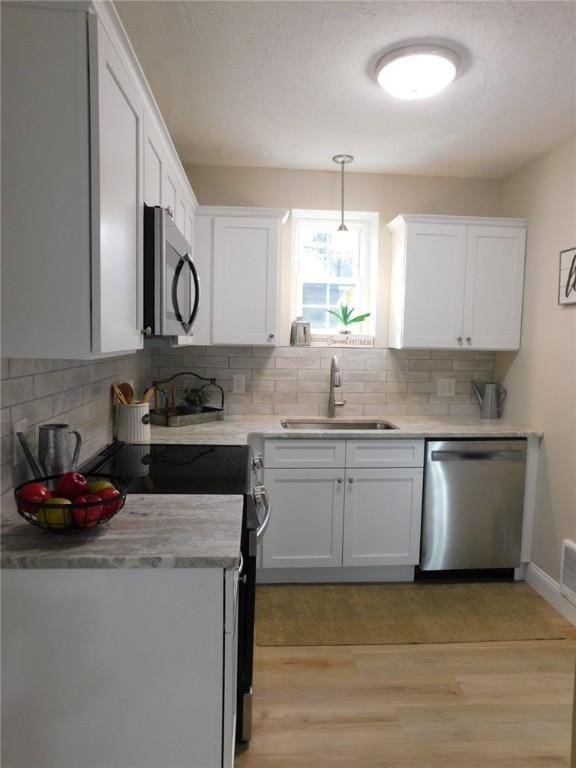 kitchen featuring a sink, light wood-style floors, appliances with stainless steel finishes, and white cabinetry