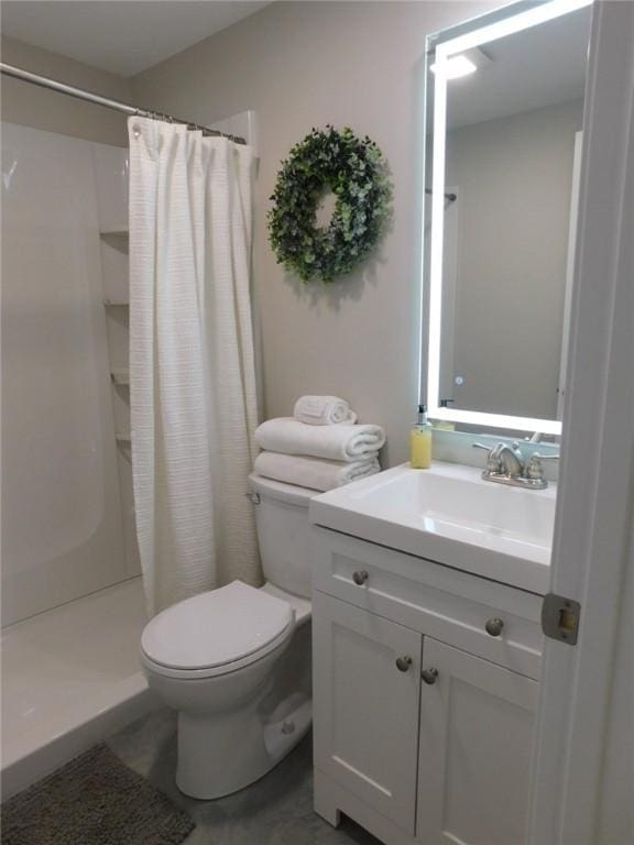 bathroom with a stall shower, toilet, and vanity