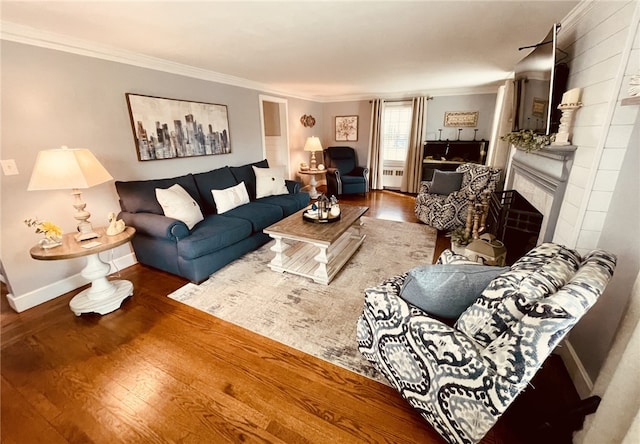 living area featuring baseboards, a fireplace, wood finished floors, and crown molding