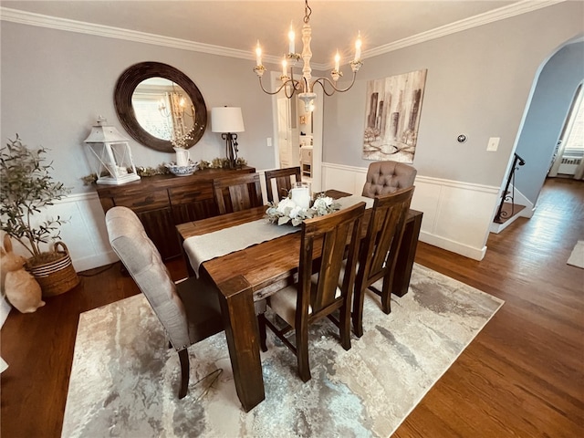 dining space featuring arched walkways, a notable chandelier, wood finished floors, and wainscoting