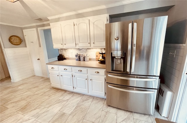 kitchen featuring light countertops, wainscoting, white cabinetry, crown molding, and stainless steel fridge