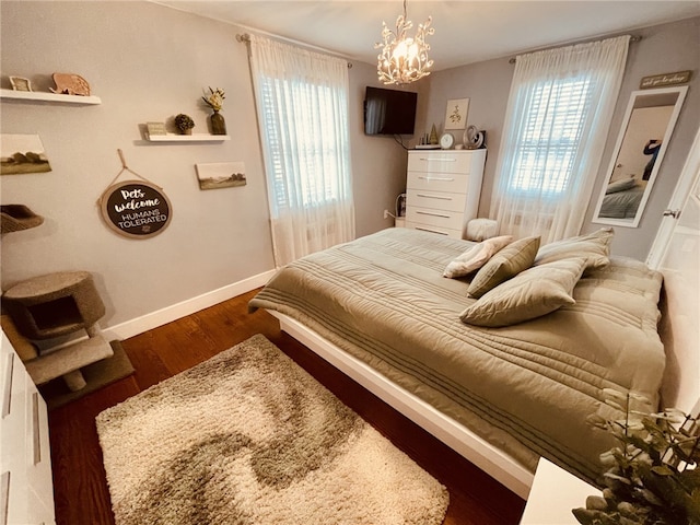 bedroom featuring an inviting chandelier, multiple windows, wood finished floors, and baseboards