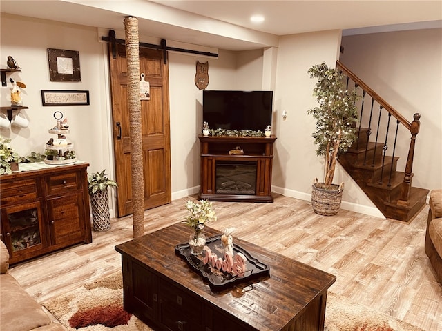 living area featuring light wood finished floors, baseboards, stairs, recessed lighting, and a glass covered fireplace