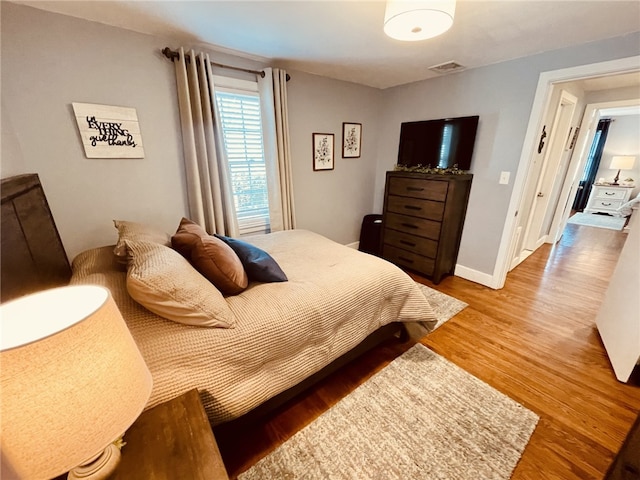 bedroom with visible vents, baseboards, and wood finished floors