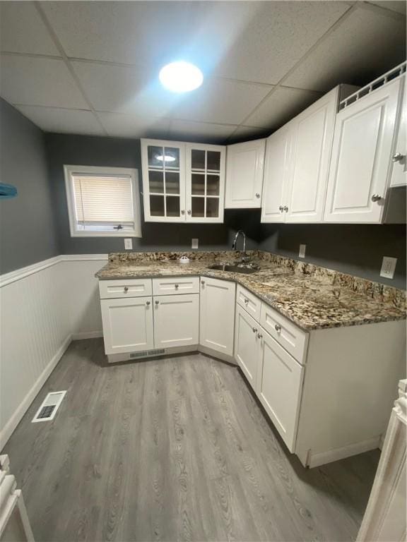 kitchen with a sink, visible vents, light wood-type flooring, and a drop ceiling