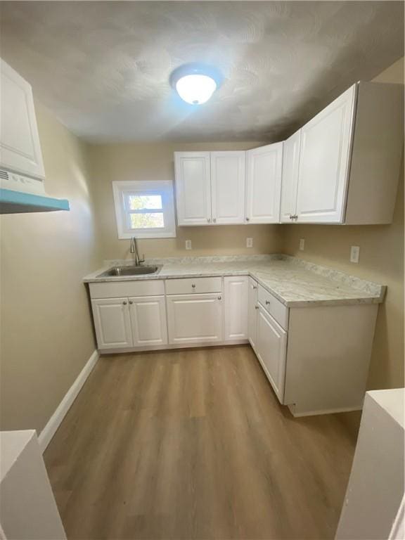 kitchen featuring light countertops, white cabinets, light wood-style flooring, and a sink