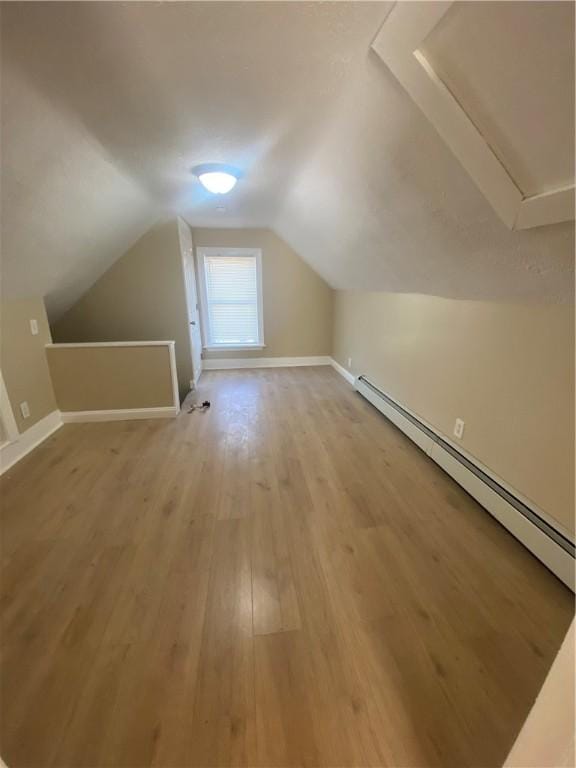 bonus room with lofted ceiling, light wood-style flooring, baseboards, and a baseboard radiator