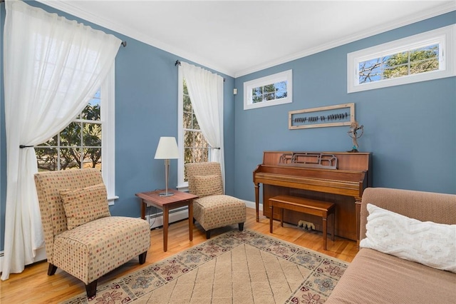 sitting room with a baseboard heating unit, crown molding, baseboards, and wood finished floors