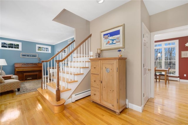 staircase featuring a healthy amount of sunlight, wood finished floors, baseboards, and a baseboard radiator