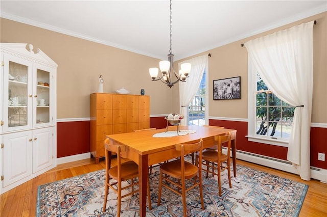 dining area with crown molding, plenty of natural light, light wood-style floors, and a chandelier