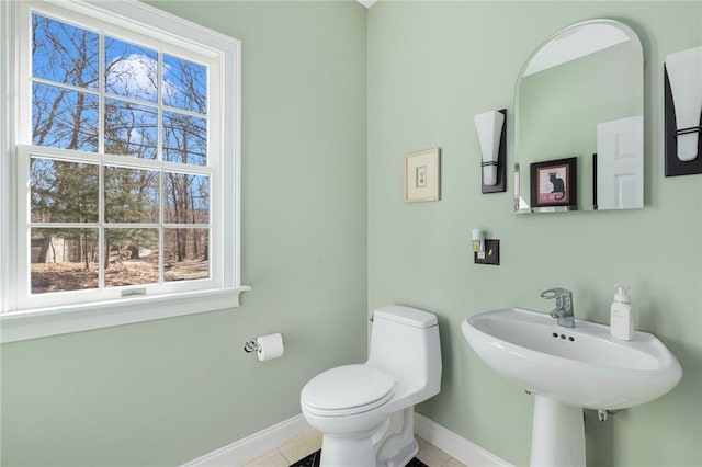 bathroom with tile patterned floors, toilet, baseboards, and a sink