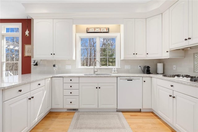 kitchen with white cabinetry, white appliances, light wood-style floors, and a sink