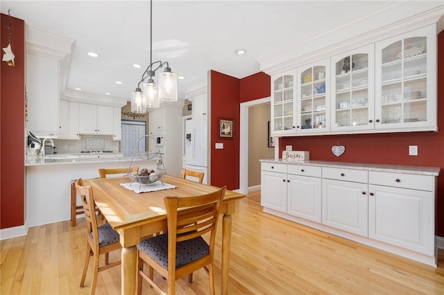 dining area with light wood finished floors, crown molding, baseboards, recessed lighting, and a notable chandelier