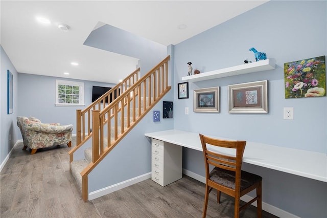 office space featuring baseboards, wood finished floors, and built in study area