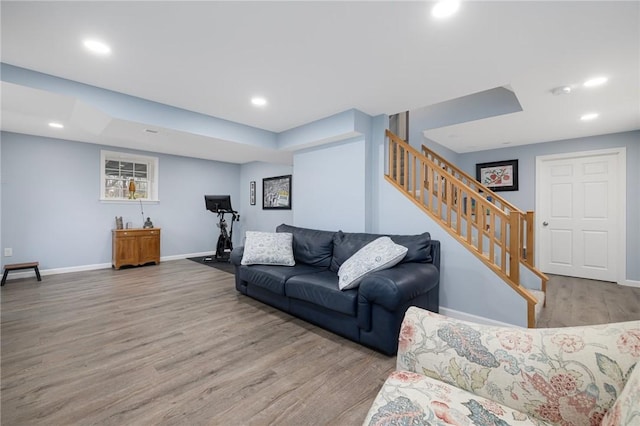 living area with recessed lighting, baseboards, wood finished floors, and stairs